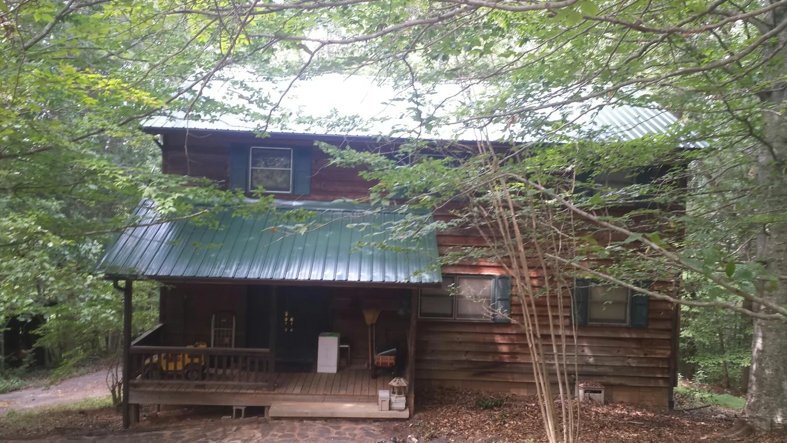 Green metal roof and covered porch on a log cabin in Scotch Plains