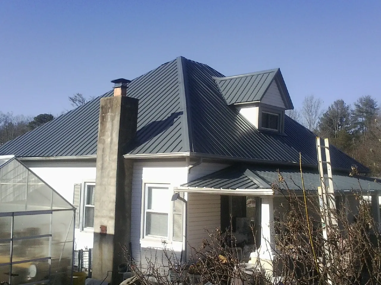 Dark blue standing seam metal roof on a white farmhouse with dormer — Slate & Tile Roof Repair by Roofing Brothers in Scotch Plains