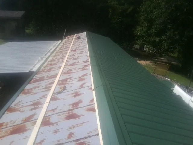 Old rusted panels beside newly installed green metal roofing — Wind Damage Roof Repair by Roofing Brothers in Scotch Plains