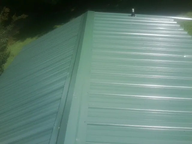 New green metal panels meeting at the ridge of a roof — Flat Roof Repair work by our crew in Scotch Plains