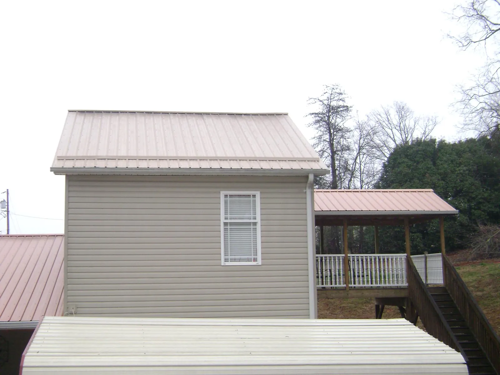 Tan metal roofs on a two story addition and attached porch, from a Roof Replacement job in Scotch Plains