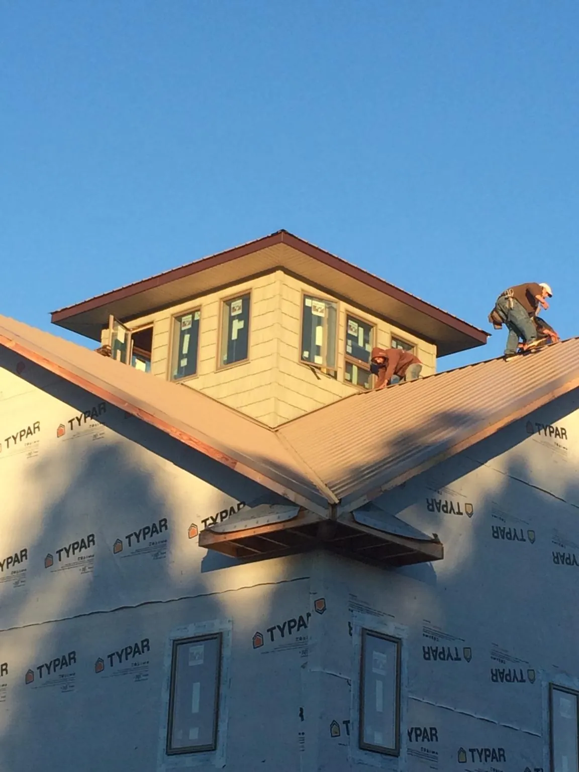 Roofers working around a rooftop cupola on a new metal roof at sunset — Roof Waterproofing in Scotch Plains by Roofing Brothers